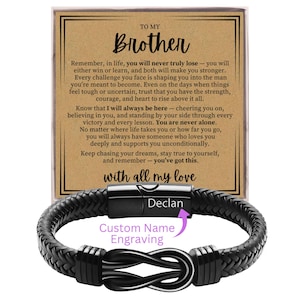 May include: A black braided leather bracelet with a stainless steel clasp, engraved with the name "Declan." The bracelet is presented with a card that reads "To My Brother" and a heartfelt message. The words "Custom Name Engraving" are also visible.