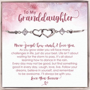 May include: A silver bracelet with two intertwined heart charms and a clear crystal charm. The bracelet comes in a gift box with a pink and white floral design and a message that reads "To My Granddaughter Never forget how much I love you. As you grow older you will face many challenges in life, just do your best. Life isn't about waiting for the storm to pass, it's all about learning how to dance in the rain. Every day may not be good, but find something good in every day. Laugh, love, live. Follow your dreams, believe in yourself, and remember to be awesome. I'll always be with you. Love You Forever ♡"