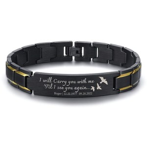 May include: Black and gold stainless steel bracelet with an engraved message: "I will Carry you with me 'Til I see you again... Roger | 12.22.1977 - 09.20.2022". Two small birds are engraved on the bracelet.