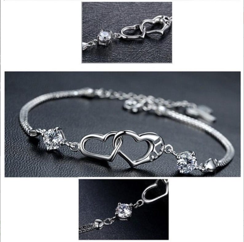 May include: Silver bracelet with two interlocking heart charms and clear cubic zirconia stones.
