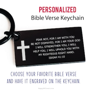 以下が含まれることがあります： 黒い長方形のキーホルダー。白い十字架とイザヤ41:10からの聖書の詩が刻まれています。「PERSONALIZED Bible Verse Keychain」の文字が上部にあり、下部に追加のテキストがあります。