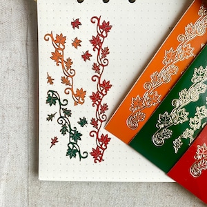 May include: Three sheets of decorative paper with gold foil accents. Each sheet features a repeating pattern of stylised leaves and vines in different colours: orange, green, and red.