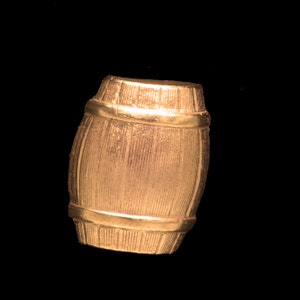 May include: A gold-colored metal barrel-shaped ornament. The barrel has a textured surface and is detailed with a thin gold band around the top and bottom.