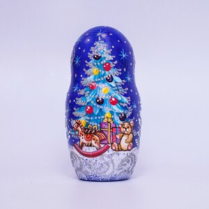 May include: A blue and silver painted wooden Russian nesting doll, or matryoshka, with a Christmas tree, rocking horse, and teddy bear with a gift.