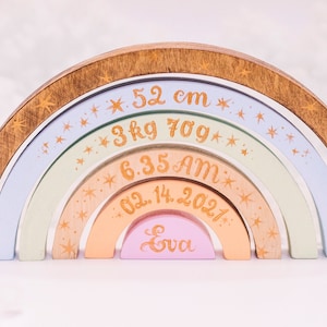 May include: A rainbow-colored wooden arch with gold stars and the text "52 cm", "3 kg 70g", "6:35 AM", "02.14.2021", and "Eva".