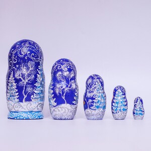 May include: A set of five blue and silver Russian nesting dolls, or matryoshka dolls, with a winter forest scene painted on them. The dolls are arranged in order of size, with the largest doll on the left and the smallest doll on the right.