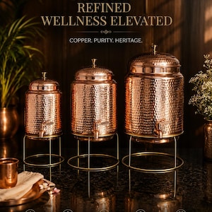 Könnte beinhalten: Drei Kupfer-Wasserspender in verschiedenen Größen, jeweils mit gehämmerten Oberflächen und einem Zapfhahn. Sie stehen auf goldfarbenen Metallständern. Der Text lautet: „TRADITION REFINED WELLNESS ELEVATED“.