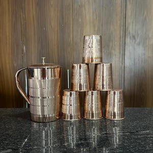 Könnte beinhalten: Eine weiße Keramik-Tasse mit schwarzem Henkel und dem Text "But First, Coffee" in handschriftlichem Stil. Die Tasse steht auf einer weißen Oberfläche. Die Tasse ist 10 cm hoch.