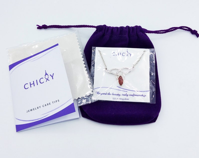 K&ouml;nnte beinhalten: Eine Halskette aus Sterlingsilber mit einem marquise-geschliffenen rotbraunen Steinanh&auml;nger, verpackt in einer transparenten Kunststoffh&uuml;lle mit CHICXY-Markenkarte. Enth&auml;lt einen violetten Samtbeutel und ein Schmuckpflegeheft.