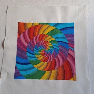 Può includere: Un disegno a punto croce quadrato e colorato con un motivo a spirale arcobaleno. Il design utilizza uno spettro di colori, tra cui rosso, arancione, giallo, verde, blu e viola. Il punto croce è posto su uno sfondo di tessuto bianco.
