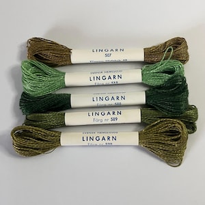 Könnte beinhalten: Fünf Spulen Lingarn Stickgarn in Grün- und Brauntönen. Jede Spule hat ein weißes Etikett mit dem Markennamen und der Farbnummer. Die Farben reichen von hellgrün bis dunkeloliv.