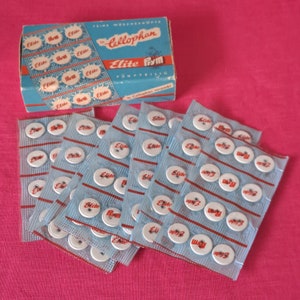 Buttonbox met 9 oude linnen buttonkaarten. Allemaal in cellofaan. 12 knoppen op elke kaart. Duits door "Prym" genaamd Elite. 22 regels. 108 knoppen.