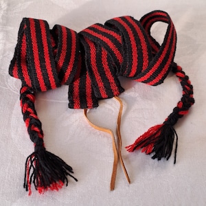 Ruban pour chaussures tissé à la main/tablette. Bordure viking en laine. Fabriquée dans le nord de la Suède dans les années 1970. Motif rayé en rouge et noir.