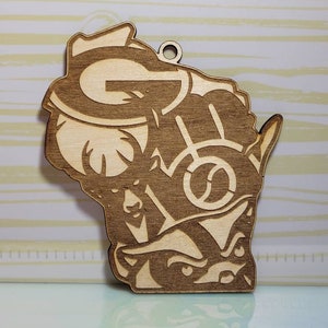 May include: A wooden ornament shaped like the state of Wisconsin with the Green Bay Packers logo, a Wisconsin Badger, and a badger. The ornament has a hole at the top for hanging.