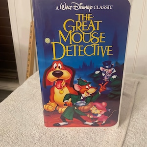 May include: A VHS tape case for the Walt Disney Classic movie "The Great Mouse Detective". The case features a colorful illustration of Basil of Baker Street, Dr. Dawson, and a dog.