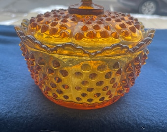 May include: Amber glass candy dish with a domed lid and a knob on top. The dish is covered in small raised dots.