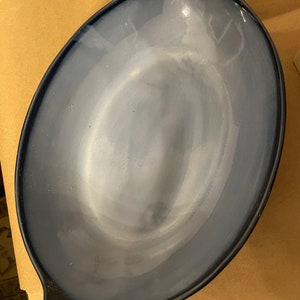 May include: A blue oval baking dish with two handles. The dish is made of ceramic and has a glazed finish.