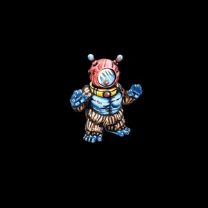 May include: A small, hand-painted toy figure of a creature wearing a red and blue helmet with a large, clear visor. The creature has brown fur and blue arms and legs.