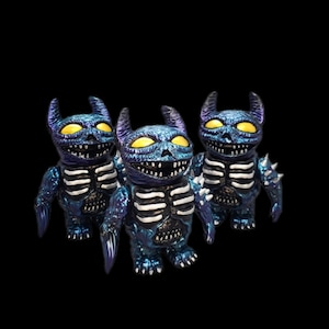May include: Three small, blue and purple, skeletal, demon-like figures with yellow eyes. The figures have wings and horns.
