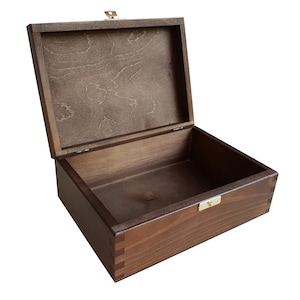 May include: A wooden box with a hinged lid and a brass latch. The box is made of dark brown wood and has a natural wood grain. The lid is open and the inside of the box is empty.