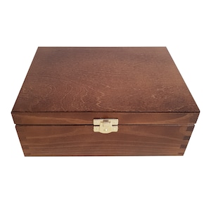 May include: A wooden box with a hinged lid and a brass latch. The box is a dark brown color and has a smooth finish.