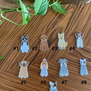 Puede incluir: Nueve parches bordados para planchar con diferentes razas de perros. Los parches est&aacute;n sobre una superficie de madera con una planta verde en el fondo.