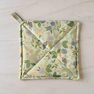 May include: A green and gold floral patterned pot holder with a loop handle.