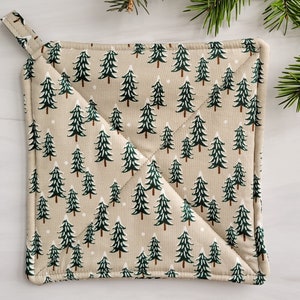May include: A beige quilted pot holder with a green and white Christmas tree pattern.