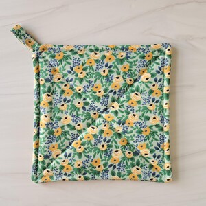 May include: A green and yellow floral patterned pot holder with a hanging loop.