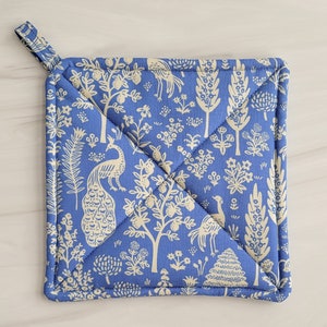 May include: Blue quilted hot pad with a white peacock and floral pattern.