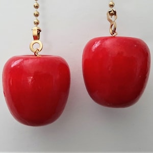 May include: Two red apple-shaped light pull chains with gold chains and connectors.