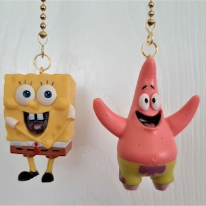 May include: Two yellow and pink cartoon character fan pull chains. The yellow character is SpongeBob SquarePants and the pink character is Patrick Star.