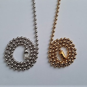 May include: Two ball chain necklaces, one silver and one gold, with a small metal clasp at the end of each chain.