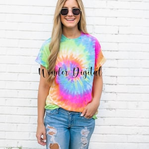 May include: A vibrant tie-dye t-shirt in a spiral pattern, featuring a blend of bright colors including pink, blue, green, and yellow. The shirt is worn with blue jeans. The text "Wonder Digital" is printed on the shirt.