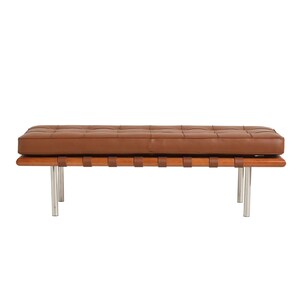 May include: A brown leather bench with a wooden frame and chrome legs. The bench has a tufted cushion and a woven leather strap design.