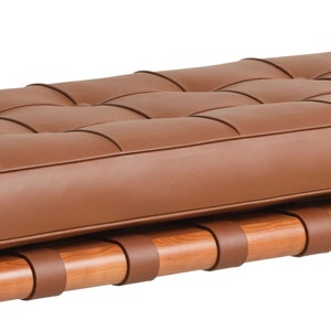 May include: A brown leather bench with a tufted top and wooden base with leather straps.