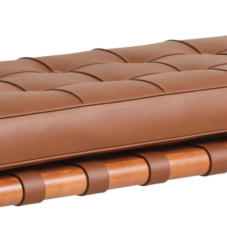 May include: A brown leather bench with a tufted top and wooden base with leather straps.