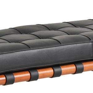 May include: A black leather bench with a tufted design and a wooden frame with black straps.