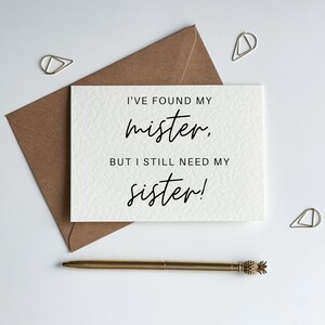 May include: A white card with black text that reads "I've found my mister, but I still need my sister!"