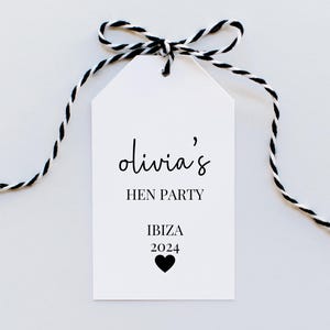 May include: White gift tag with black twine, featuring the text "Olivia's Hen Party Ibiza 2024" with a black heart.