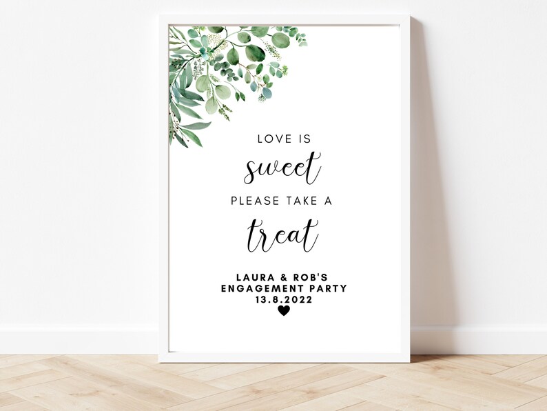 Puede incluir: Un cartel blanco con follaje verde en la parte superior. El cartel dice "Love is sweet, please take a treat, Laura & Rob's Engagement Party, 13.8.2022".
