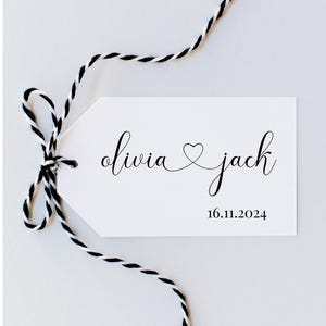 May include: White gift tag with black calligraphy that reads "olivia ♥ jack" and the date "16.11.2024". The tag is tied with black and white twine.