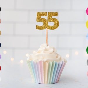 May include: Gold glitter number 55 cake topper on a rainbow cupcake.