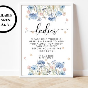 Peut inclure: Une affiche imprimable avec un motif floral dans les tons bleus et roses. L'affiche indique "ladies" et comprend le texte "Veuillez vous servir, voici un panier pour vous aider, dépêchez-vous de revenir là-bas avant de manquer la prochaine chanson." L'affiche comprend également le texte "Tara & Rob 15.04.2024".