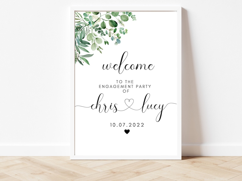 Puede incluir: Un cartel blanco con follaje verde en la parte superior. El cartel dice "Bienvenido a la fiesta de compromiso de Chris & Lucy 10.07.2022".