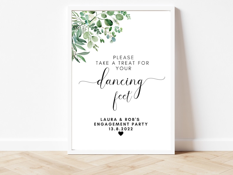 Puede incluir: Un cartel blanco con follaje verde en la parte superior. El cartel dice "Por favor, tome un dulce para sus pies danzantes". Debajo del texto se lee "Laura & Rob's Engagement Party 13.8.2022" con un peque&ntilde;o coraz&oacute;n negro.