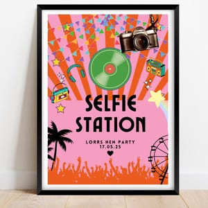 May include: A framed poster with a retro design, featuring the words "Selfie Station". The poster includes illustrations of a camera, record, headphones, and a boombox, with a pink and orange color scheme. The bottom of the poster has a crowd silhouette and a date.