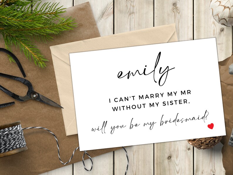 Op de afbeelding: Een witte kaart met zwarte tekst die "emily I CAN'T MARRY MY MR WITHOUT MY SISTER. will you be my bridesmaid?" zegt met een klein rood hartje.