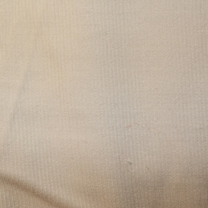 May include: A close-up of a plain, off-white fabric with a subtle, textured pattern. The fabric has a smooth, slightly shiny surface.