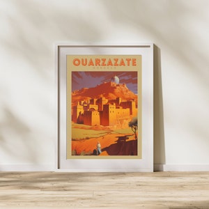May include: Framed travel poster featuring Ouarzazate, Morocco. The artwork depicts a desert landscape with a fortress and a figure in traditional clothing. The poster has a vintage style with warm, earthy tones and the text "OUARZAZATE MOROCCO".